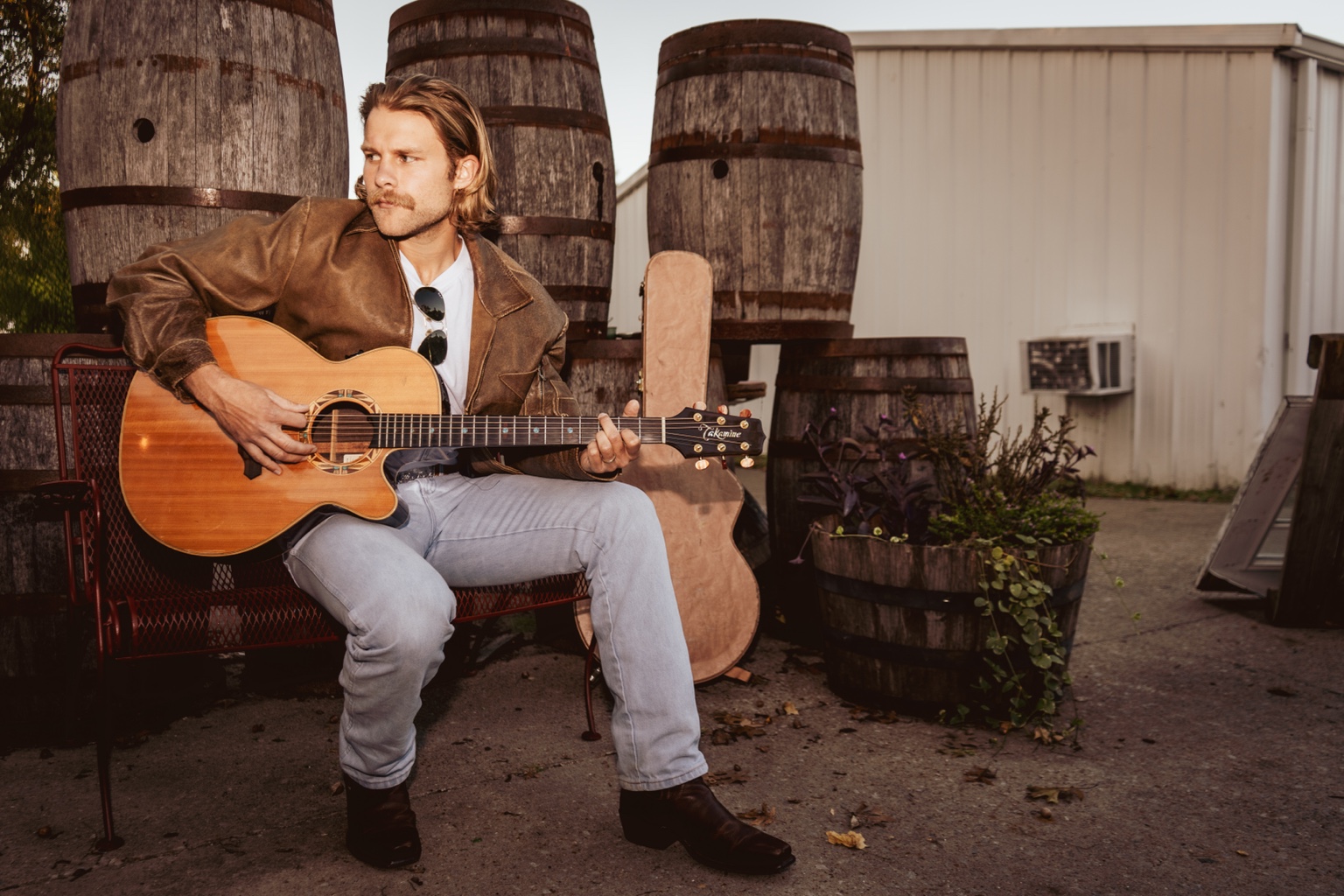Ben Cannon seated outdoors playing an acoustic guitar